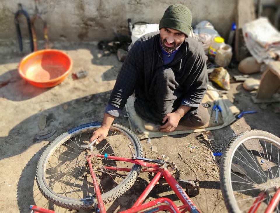With paralyzed legs, Pulwama man starts cycle repairing to earn livelihood